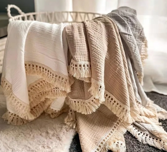 Newborn baby swaddle blankets made of cotton muslin with tassel details. Perfect for wrapping and comforting infants, serving as a sleeping quilt or bed cover.